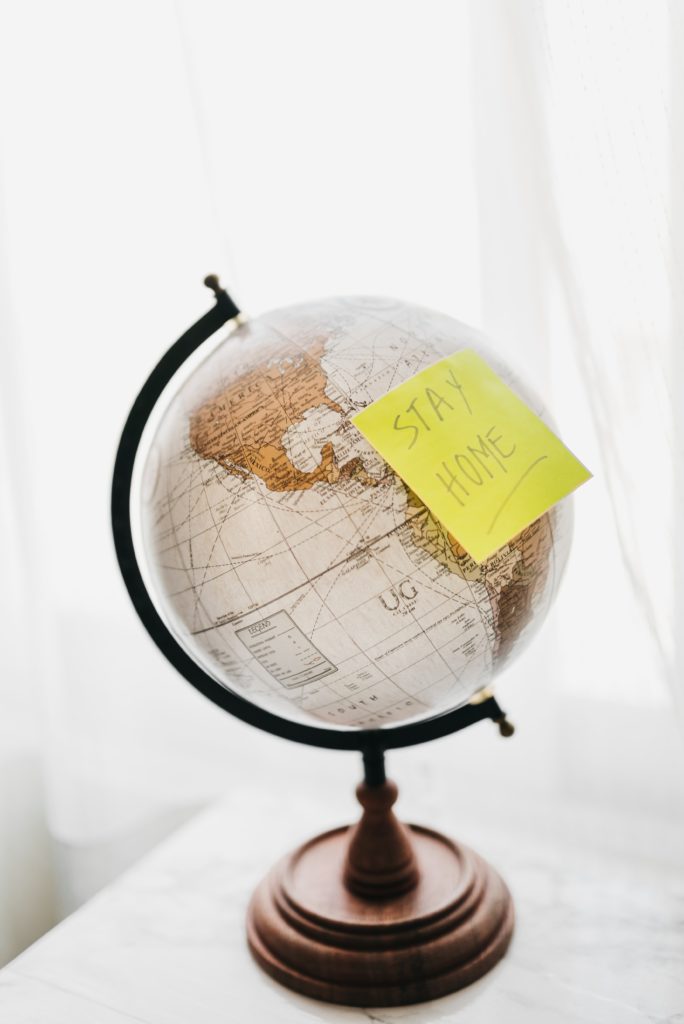 globe with a yellow sticky note saying stay home