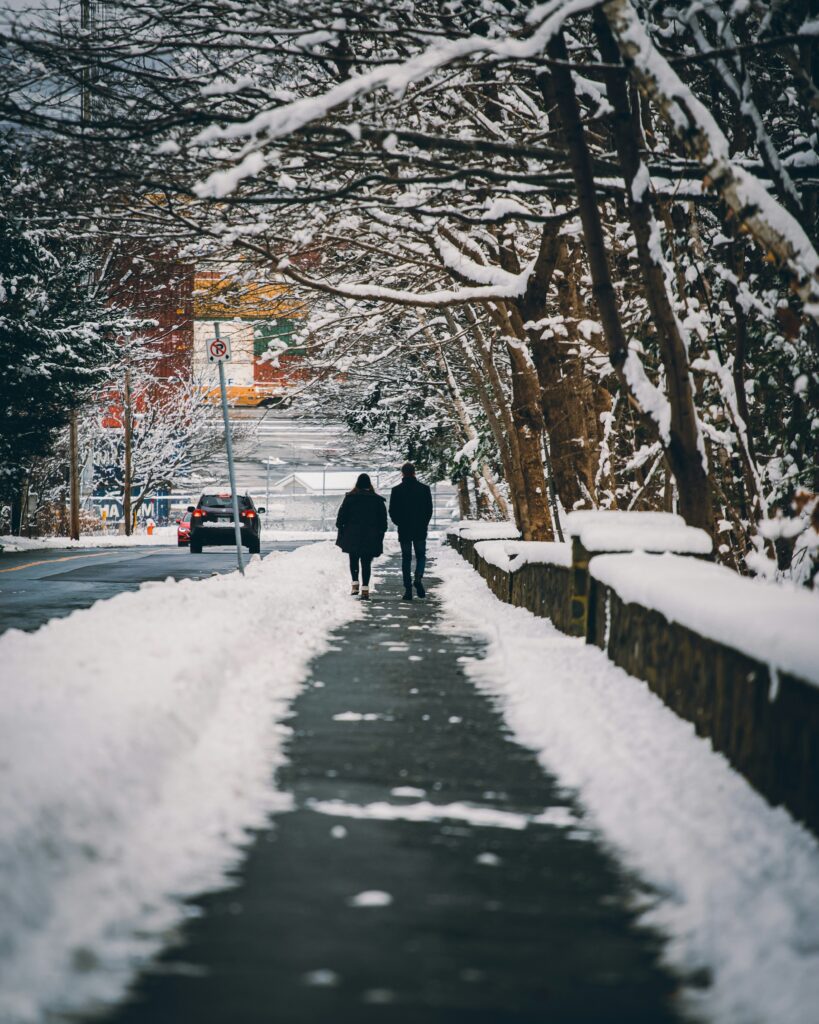 a couple walking on a pathway with snow on either sides