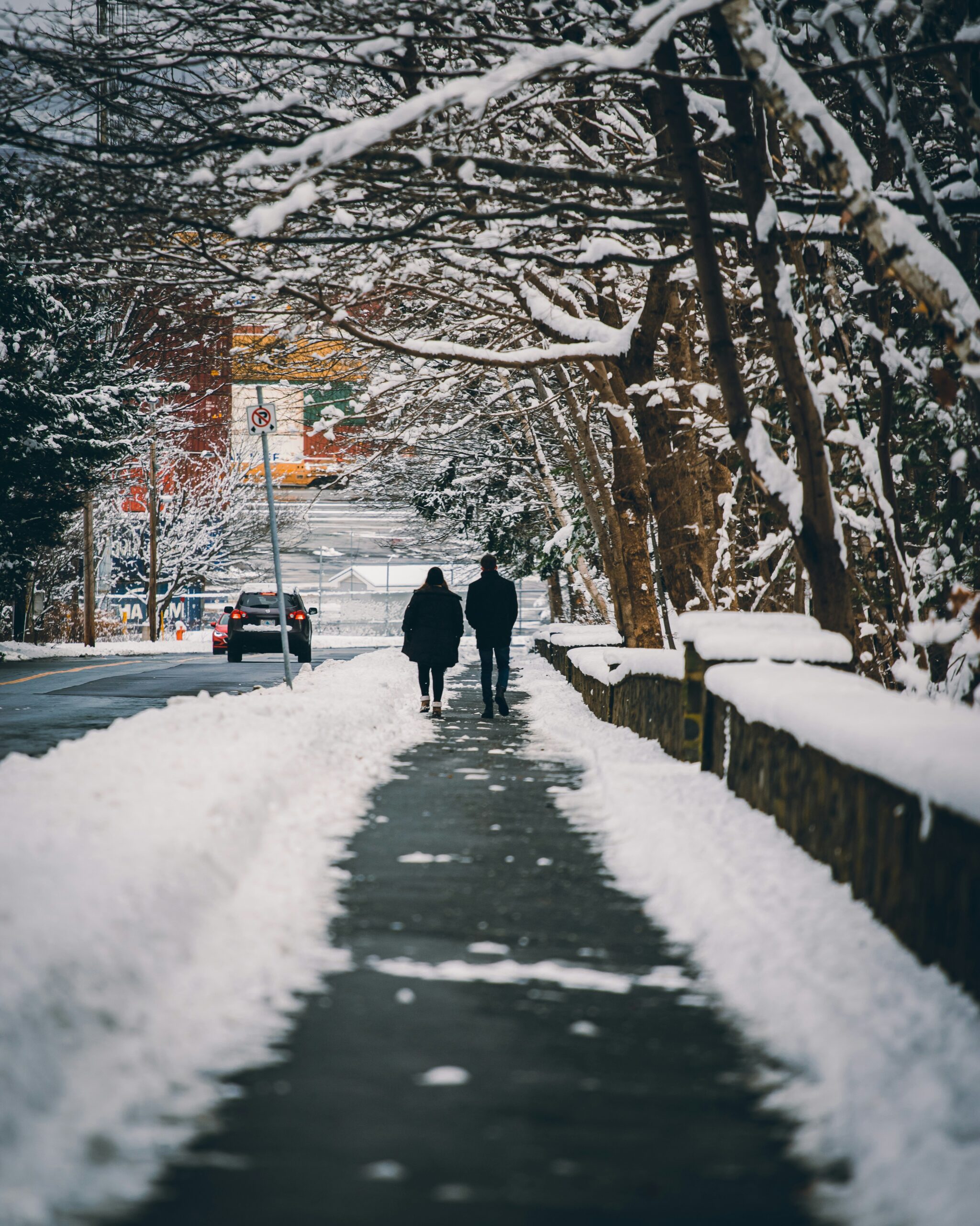 a couple walking on a pathway with snow on either sides